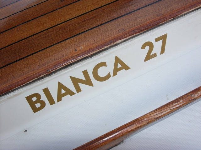 DE FLESTE BIANCA 27-sejlere har bådtype-navnet påsat siderne af lugegaragen. Bogstaverne kan du få lavet færdige til påklæbning i en skiltebutik eller hos en bådudstyrs-forhandler. Bogstaver af 